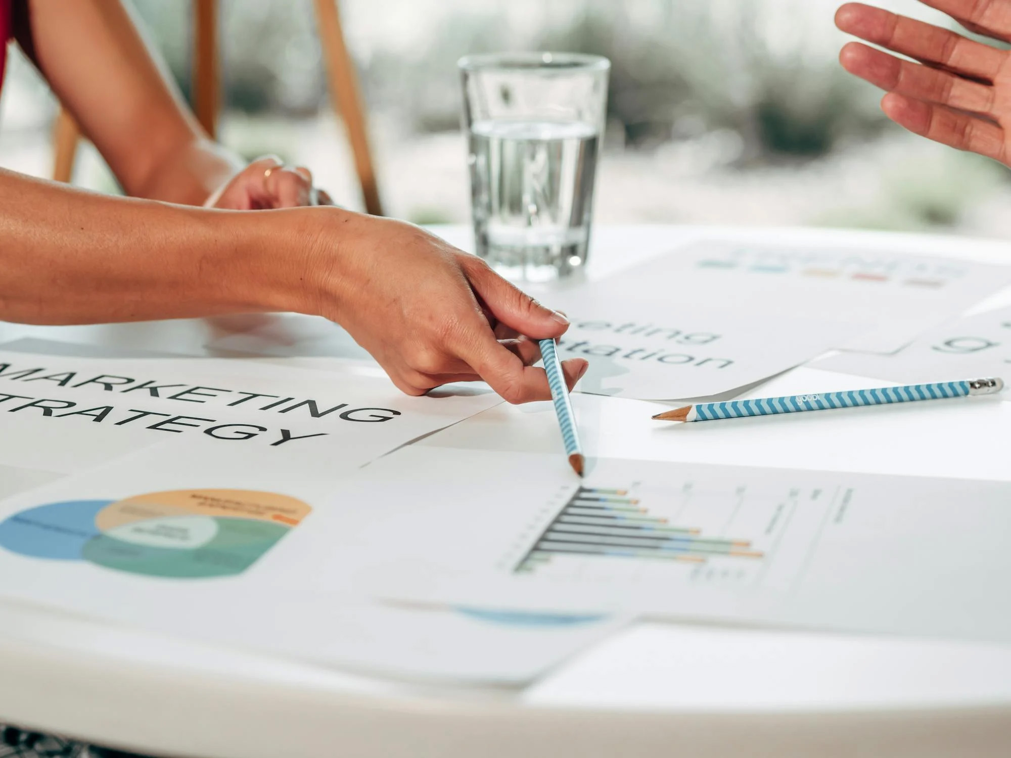 Close-up of a business meeting discussing marketing strategy with printed charts, graphs, and documents on a table
