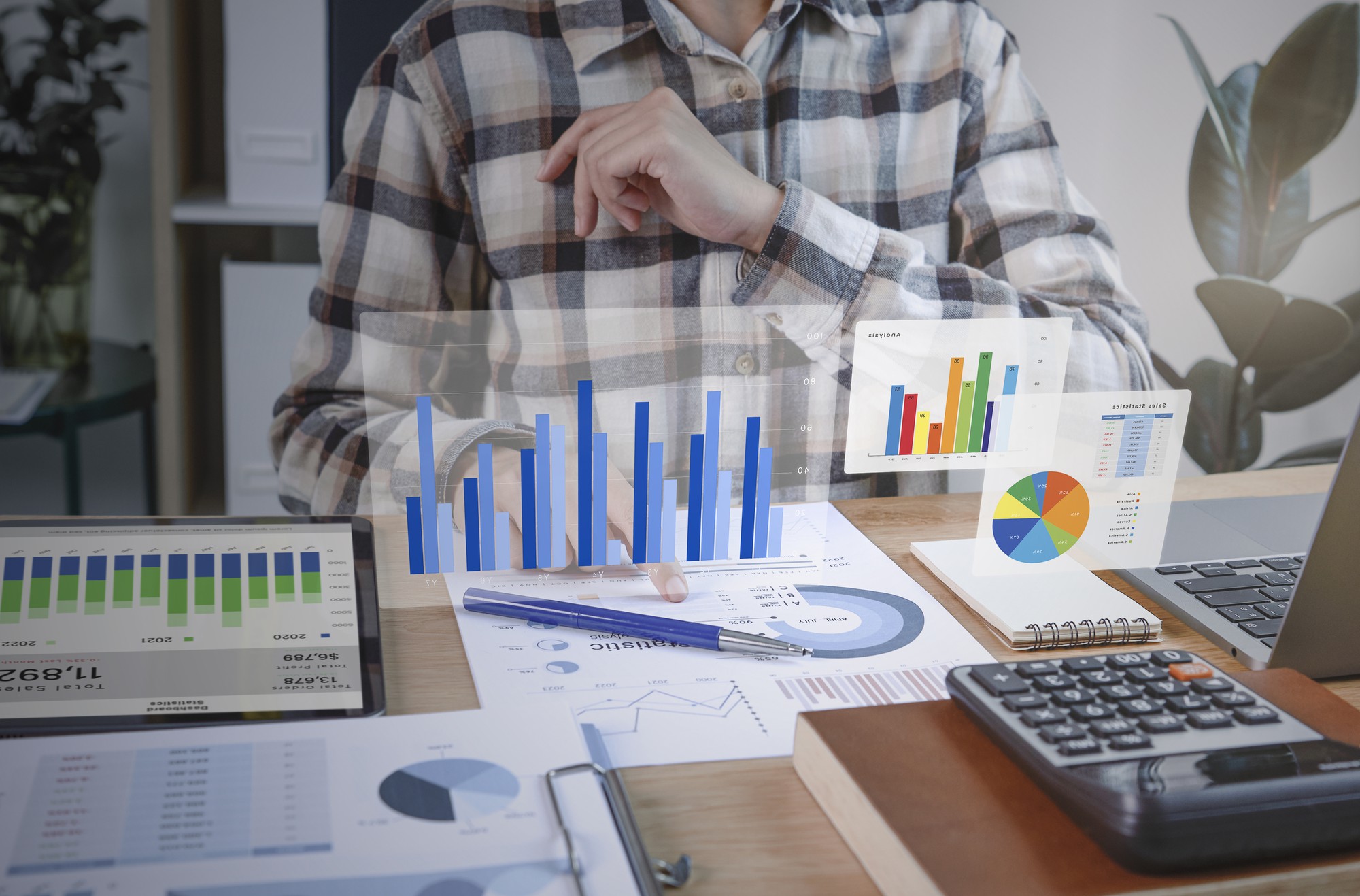 Analyst reviewing financial and business data with interactive graphs and charts on desk in modern workspace