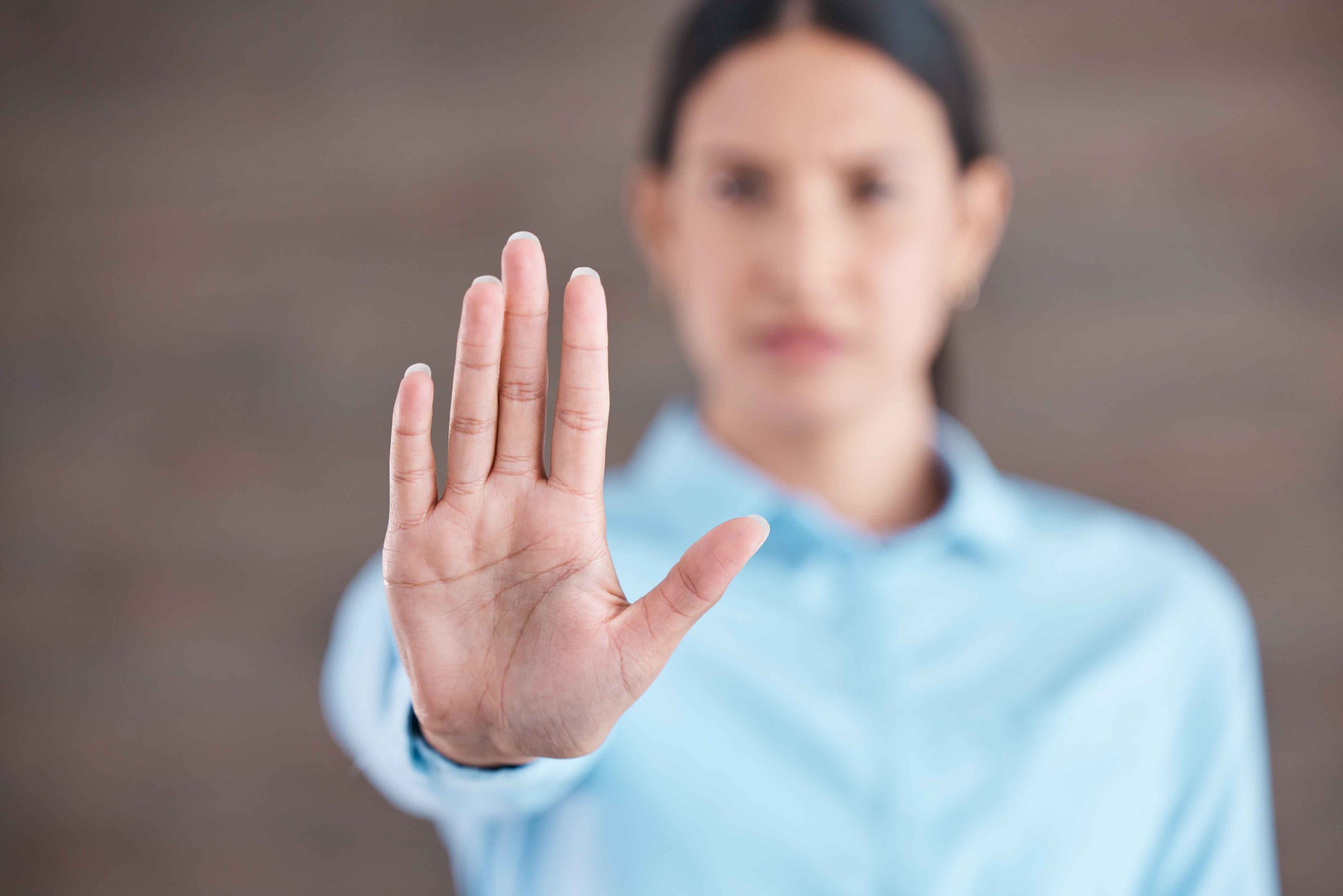 Woman raising hand with palm forward as a gesture to stop or say no, symbolizing refusal or boundary setting