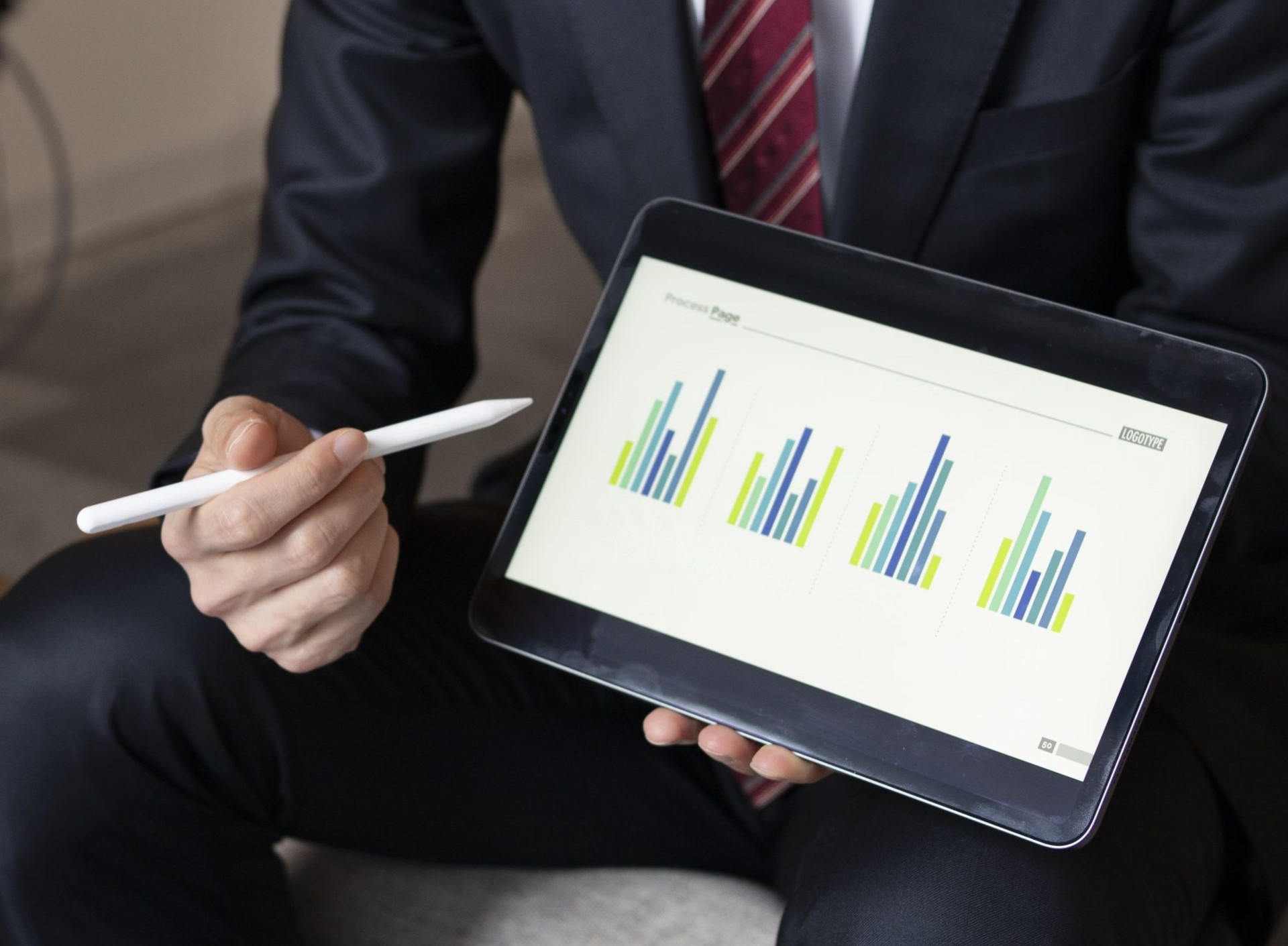 Business professional presenting bar chart data on tablet using stylus during a meeting