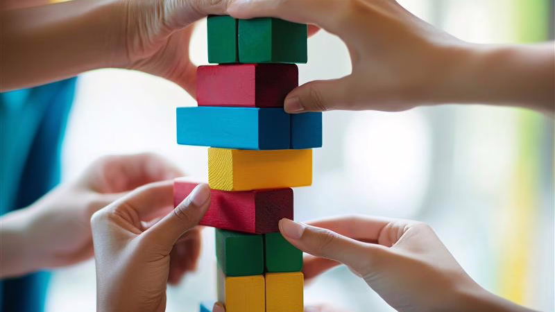 Multiple hands collaboratively building a tower with colorful wooden blocks, symbolizing teamwork and collaboration